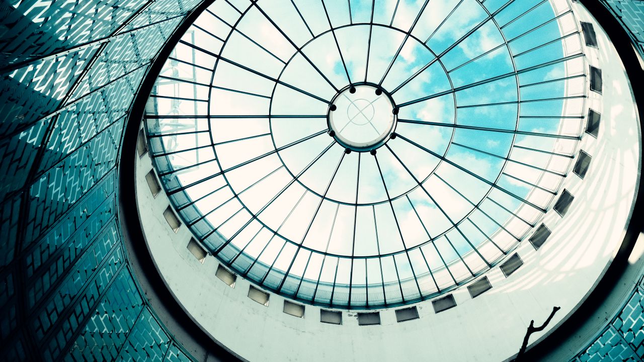 A striking view of a modern glass dome ceiling revealing the blue sky.